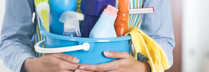 Person hält einen Eimer mit Reinigungsmitteln